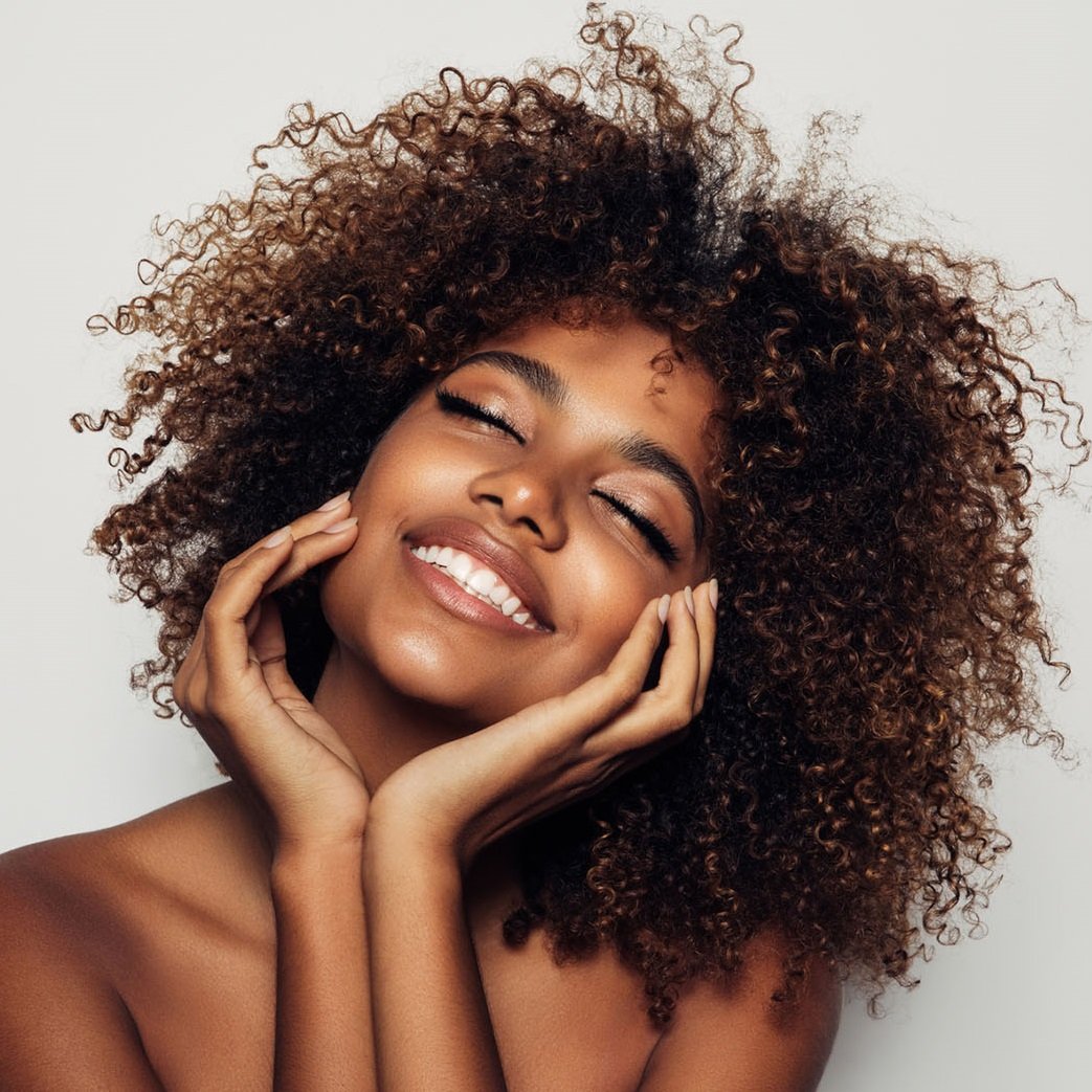 Smiling woman with voluminous curly hair.